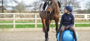 Riscaldamento del cavaliere amazzone seduta con cavallo a mano